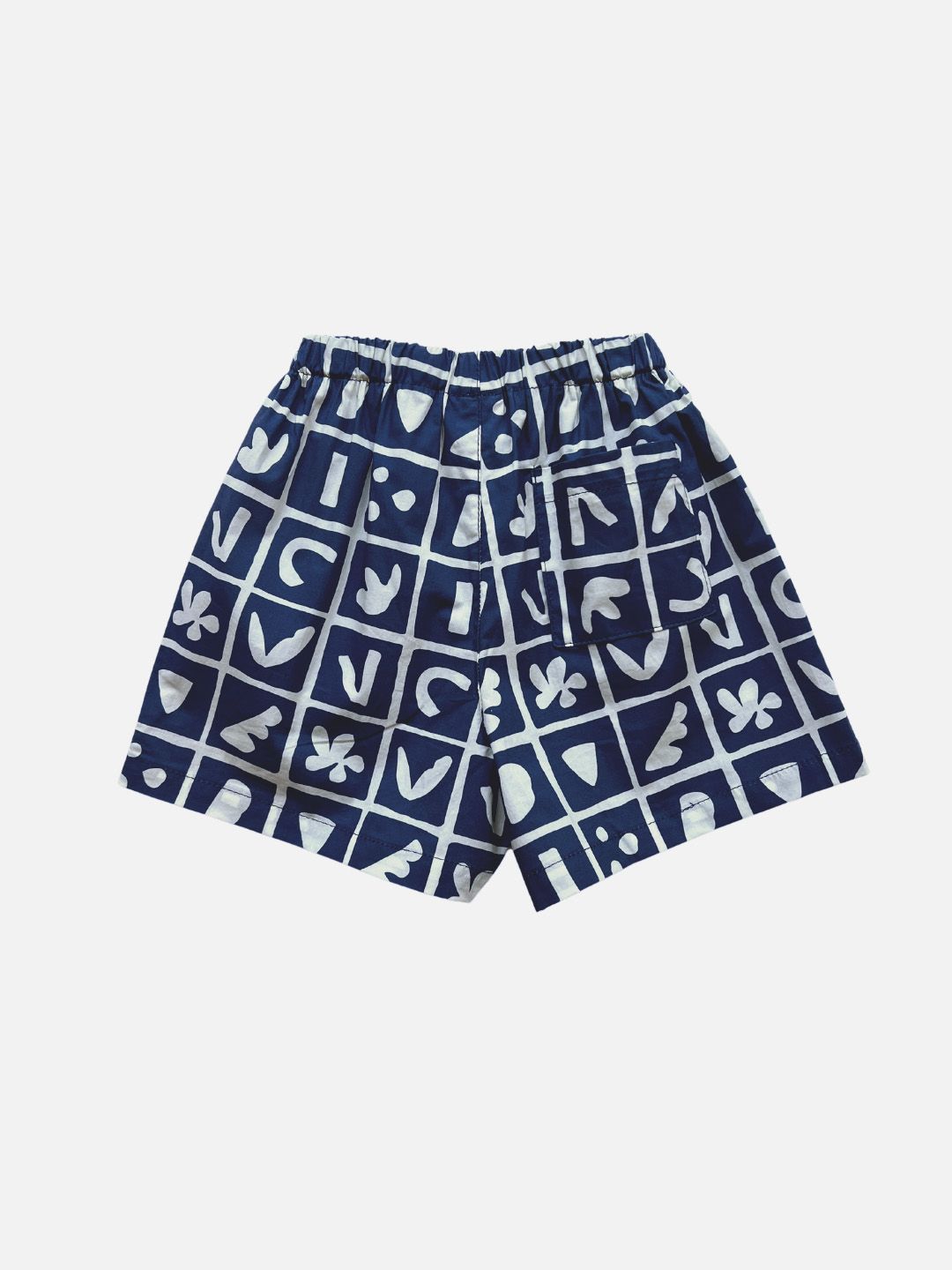 A pair of kids' shorts in deep blue, overlaid with a grid of different shapes in white, with back pocket, rear view