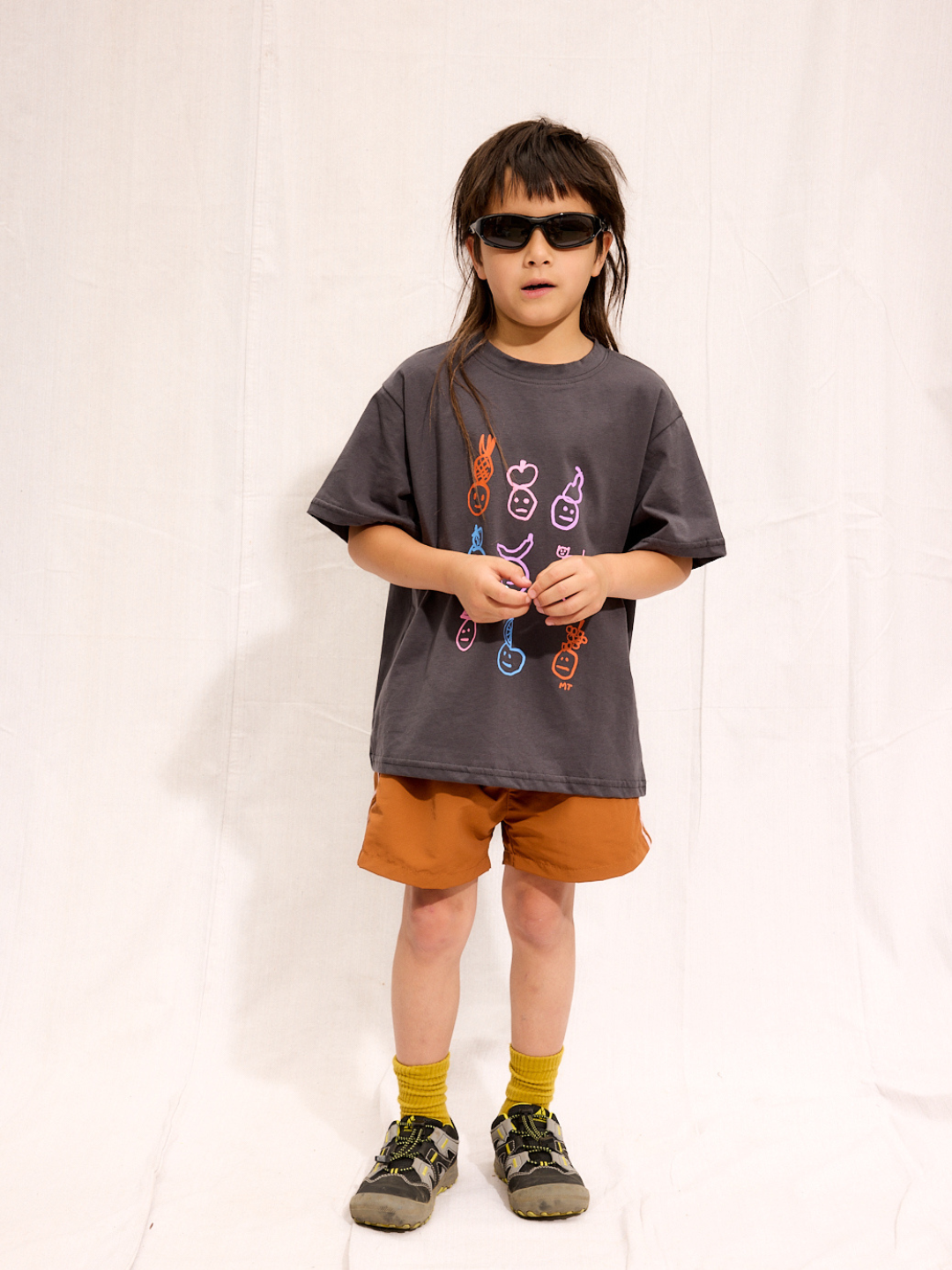A child is wearing the rust Sprinter Shorts with a charcoal fruit tee