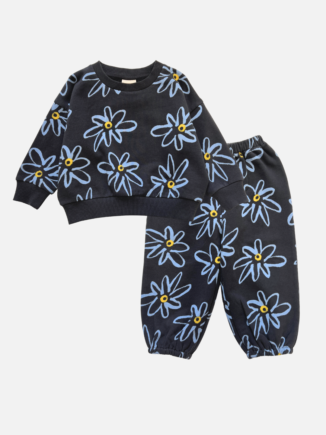 The CHARLIE SWEAT SET is a children's organic cotton sweat set in charcoal, featuring a blue and yellow painted flower print on a dark background, displayed on a white surface.
