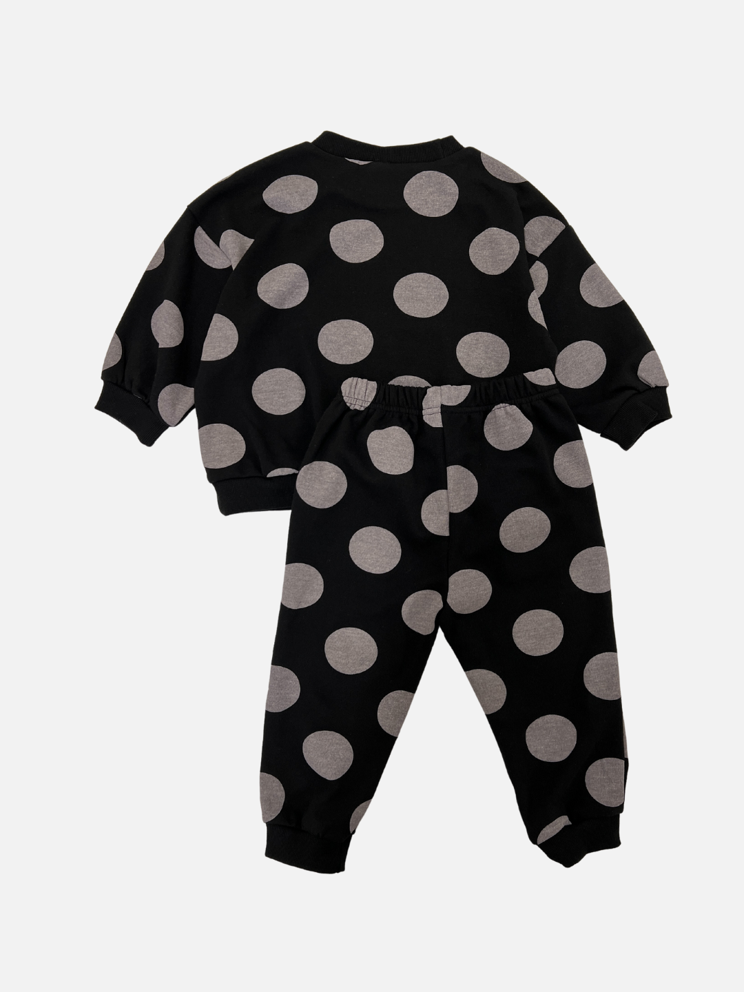 Back view of a kids sweat set in black with large grey polka dots. The set consists of a crewneck sweatshirt and a matching sweatpant.