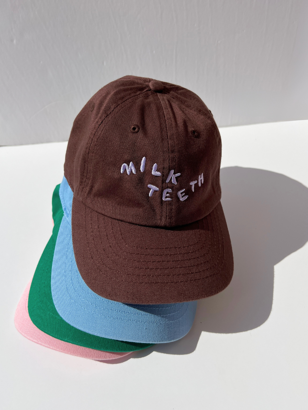 Brown | A stack of Milk Teeth embroidery caps