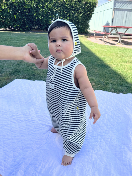 Second image of Navy | The STRIPE WAFFLE ROMPER SET, in navy, is a sleeveless baby jumpsuit made of soft waffle cotton. It features a button closure at the front, ankle snaps, and includes a matching bonnet.