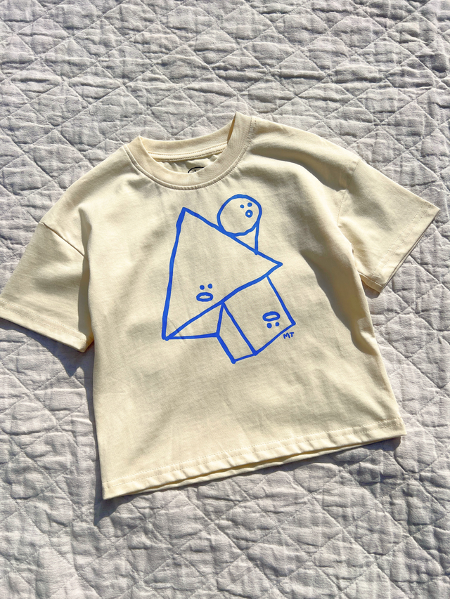 A kids' Jumble Tee laid flat on a quilt in the sun