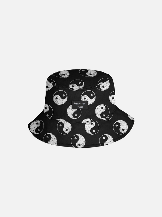 Image of A front view of the black cotton bucket hat with a yin and yang pattern all over.