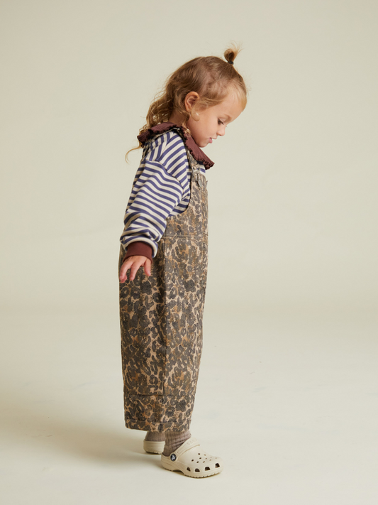 Second image of The BLYTHE LEOPARD DUNGAREE features brown leopard print, adjustable shoulder straps, and front metal buckles, displayed flat on a white background. Shipping costs may apply.