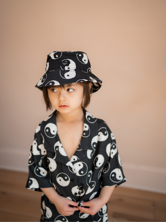 Second image of A front view of the black cotton bucket hat with a yin and yang pattern all over.