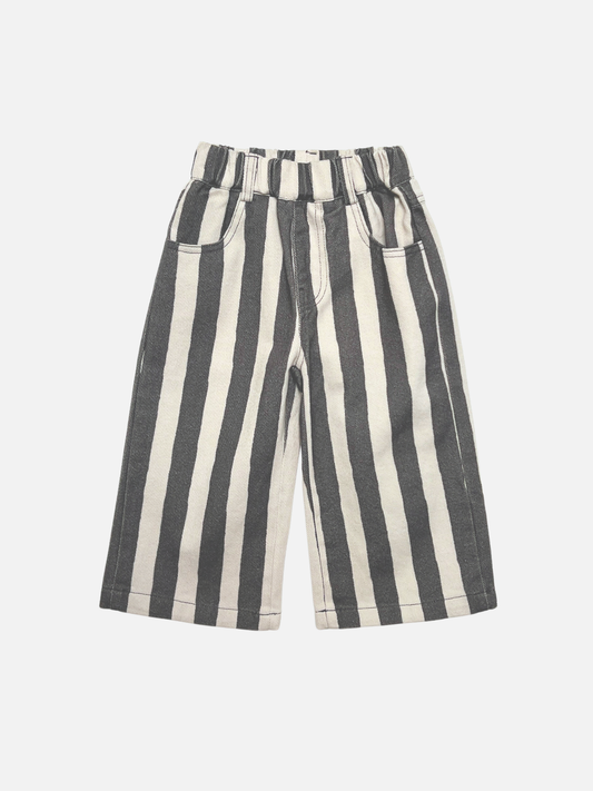 Image of A pair of wide-leg kids pants featuring bold vertical black and off-white stripes, displayed flat against a light gray background.