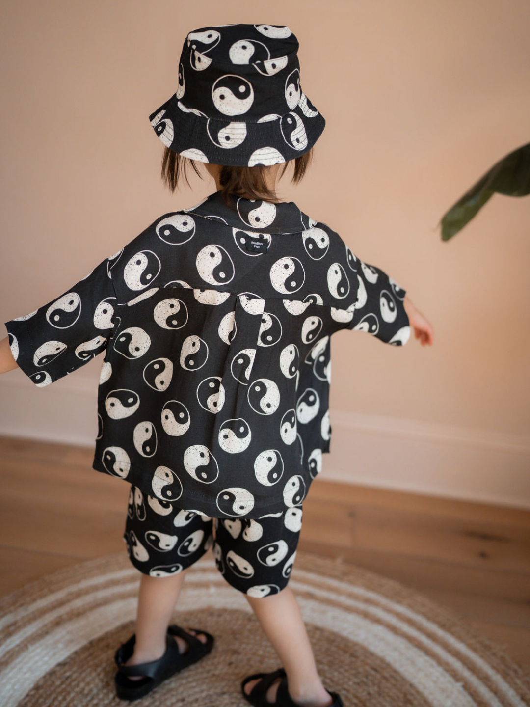 A back view of the black cotton bucket hat with a yin and yang pattern all over on a child.