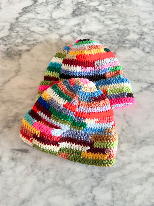 Second image of The COLOR WHEEL BEANIE in size 3-6M is a handmade hat with a multicolored patchwork, folded brim, and vibrant stripes—perfect for adding playful style to your winter wardrobe.