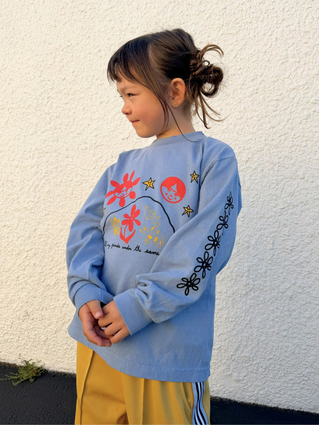 Child wearing a blue sweater with colorful designs against a white wall