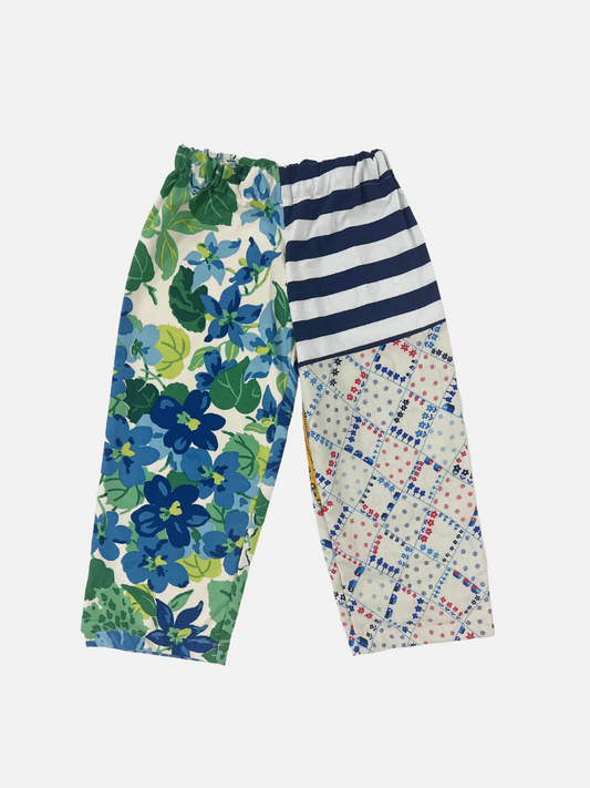 Image of Front view of kid's patchwork pant. Left leg - big floral print. Right Leg - stripes & little town print.
