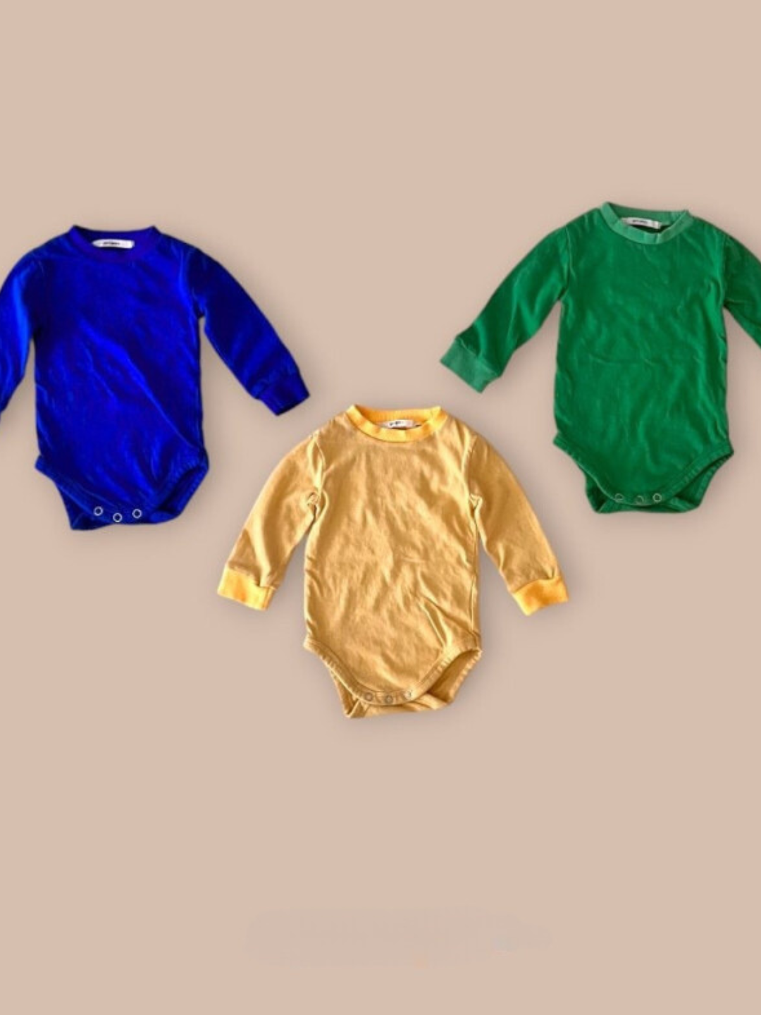 Patch onesies in blue, green, and yellow laid flat 