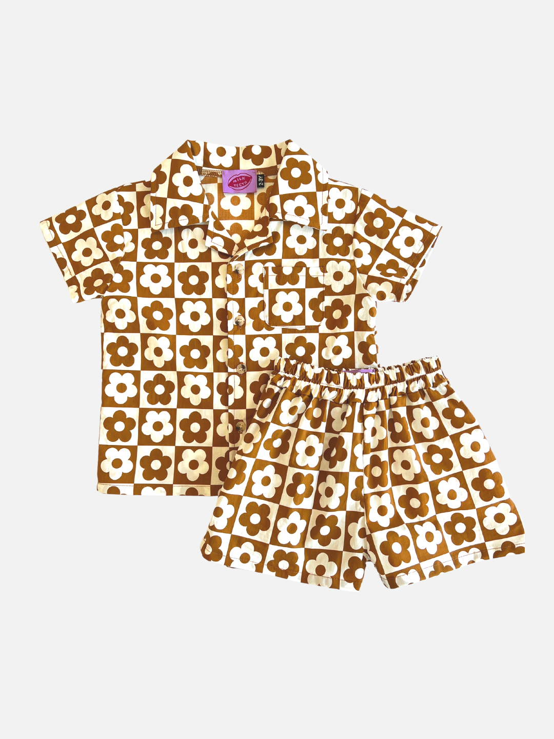 Terracotta | Set of kids' shirt and shorts in a checkerboard pattern of terracotta brown and white flowers, laid on a table,  front view