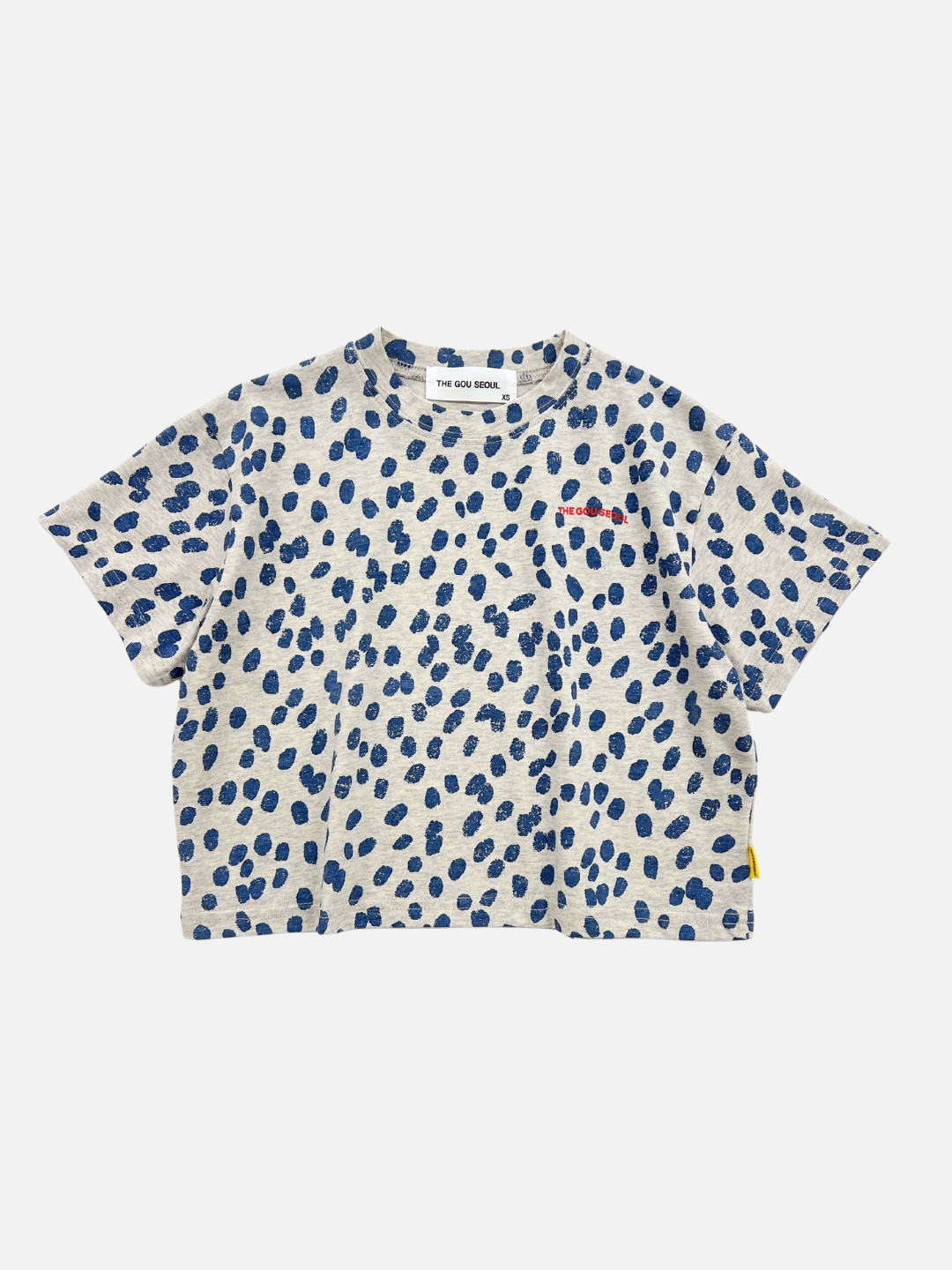 Front view of the kids' Spotted Tee. Warm pale gray background with navy blue spots all over and red The Gou Seoul writing on the right side. 