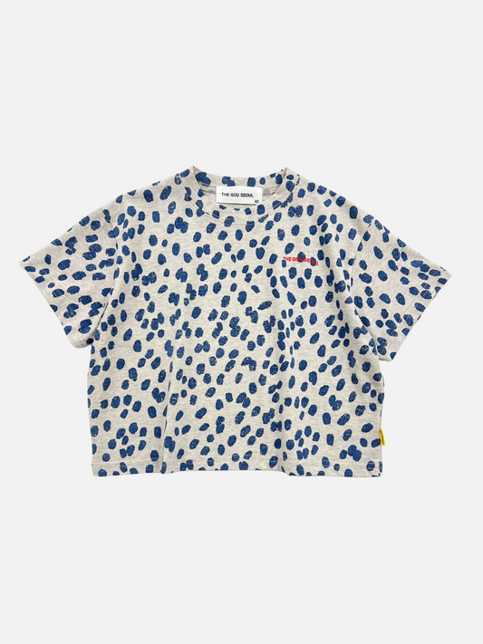 Image of Front view of the kids' Spotted Tee. Warm pale gray background with navy blue spots all over and red The Gou Seoul writing on the right side. 