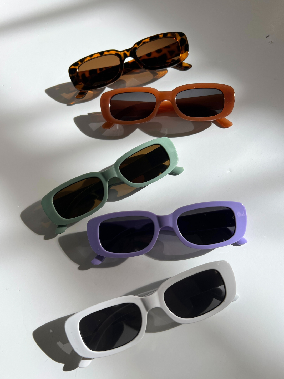 Matte Green | Five pairs of SANTA CRUZ SUNGLASSES with rectangular UV400 lenses in tortoiseshell, orange, green, purple, and white frames are neatly lined up on a white surface. Ideal for kids aged 2-6, these stylish shades offer both protection and flair for any sunny day adventure.