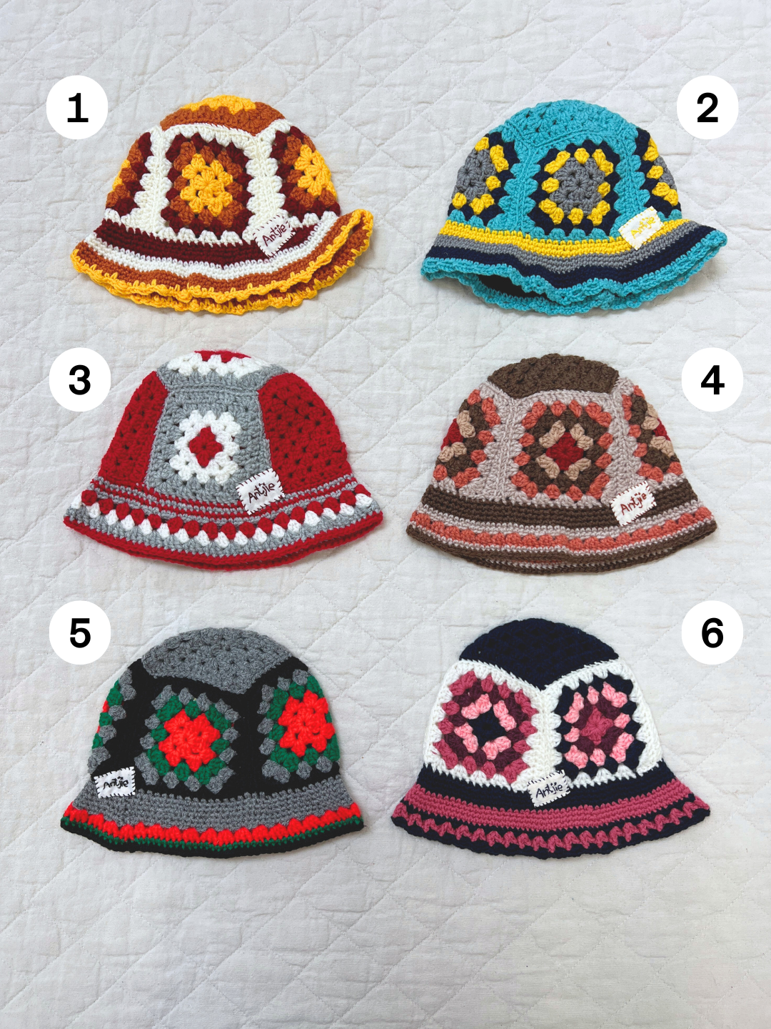 Six hand-made CROCHETED BUCKET HAT 1-3Y hats in color #1 are displayed in two rows of three, each with unique South Africa-inspired patterns, and some hats have labels attached.