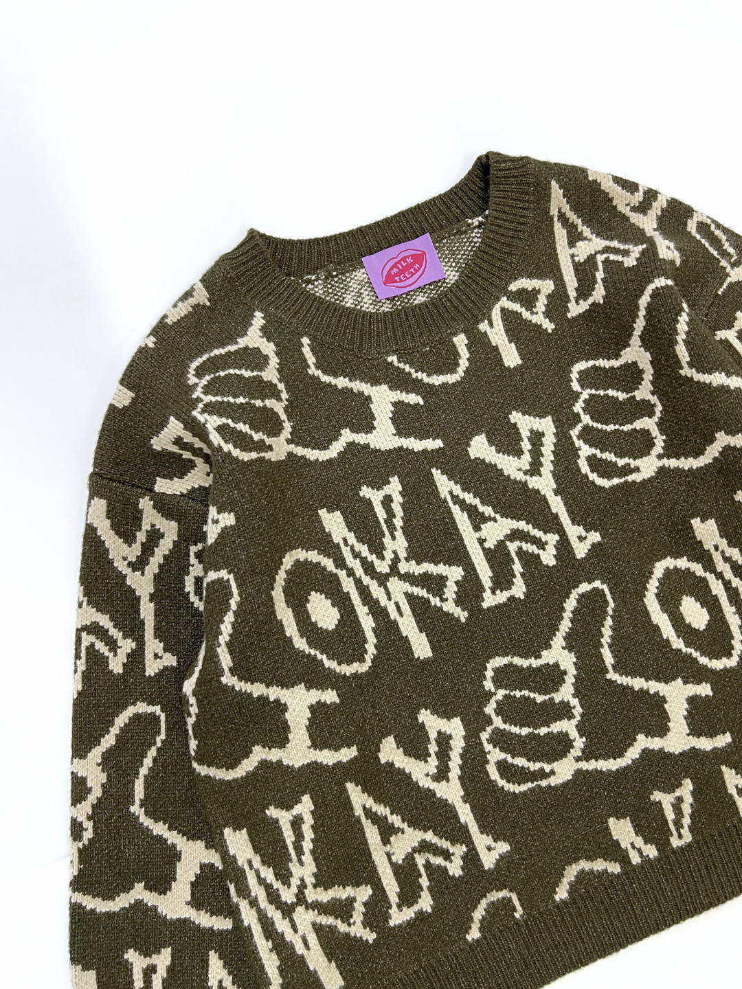 The OKAY SWEATER is a green sweater with beige "OKAY" text and thumbs-up icons, shown on a white background.