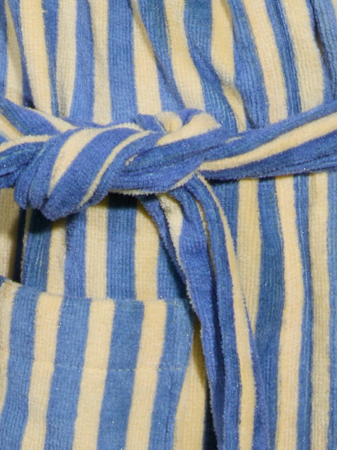 Close-up of the STRIPED ROBE, a blue and yellow striped bathrobe crafted from velvety-soft cotton, featuring a tie belt and a left-side pocket.