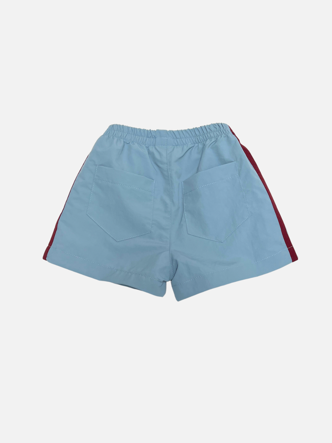 SPRINTER SHORTS in light blue, featuring an elastic waistband, two back pockets, and red side stripes, shown on a plain white background.