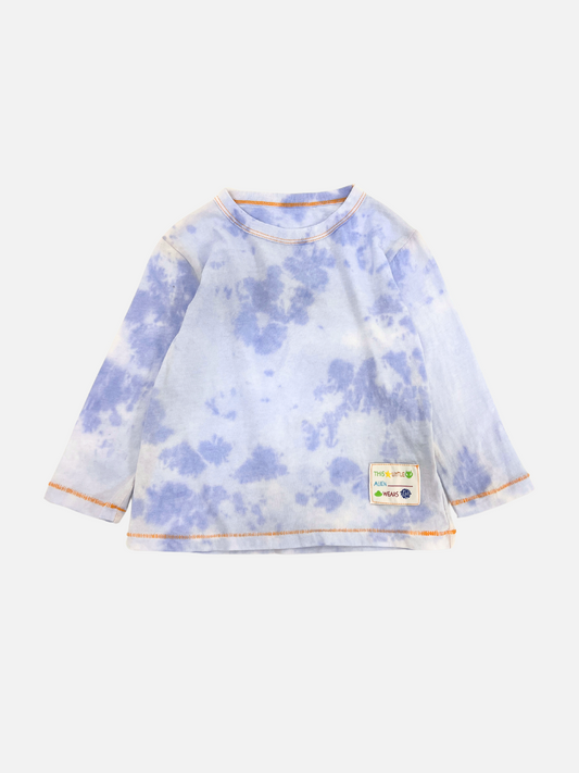 Image of The KOKO MOMO LONGSLEEVE showcases a blue and white tie-dye design, complemented by orange stitching and a small patch on the front. For a perfect fit, please refer to our product-specific size chart.