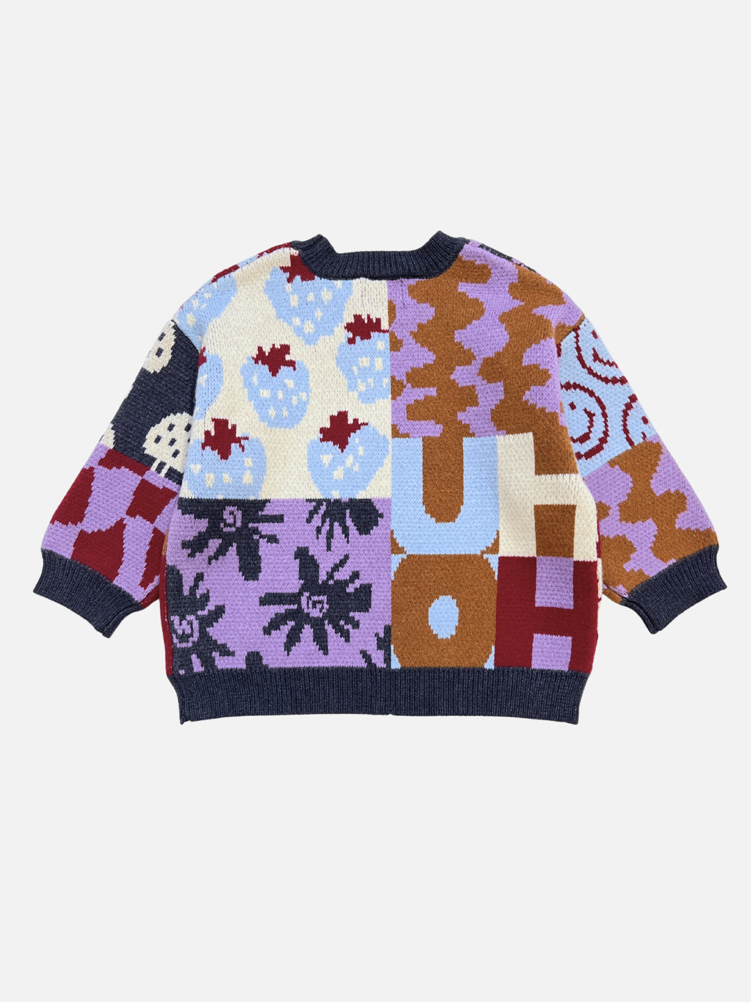 The EVERYTHING SWEATER is a colorful, oversized soft knit with bold letters and patterns like strawberries, wavy checkers, and abstract shapes on a white background.
