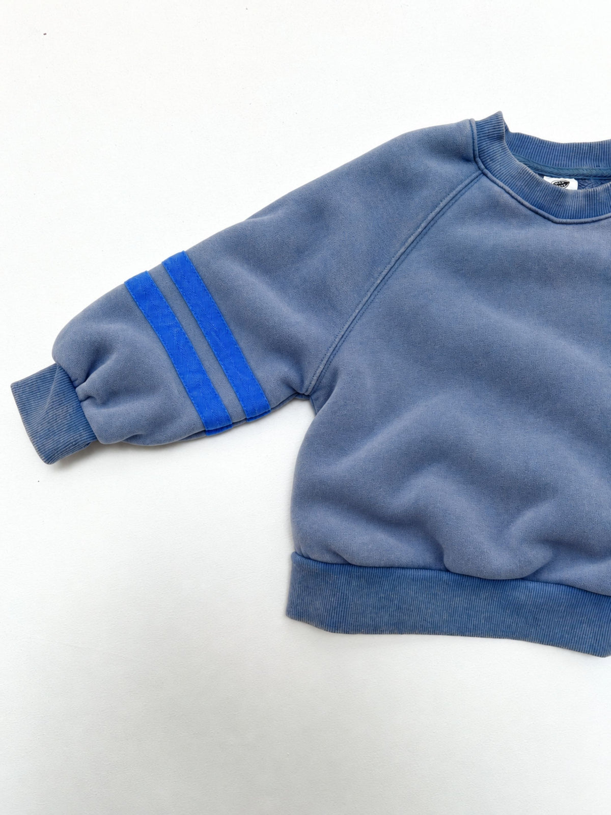 Blue | Detail view of kids crewneck sweatshirt in medium blue with two bright blue stripes on each sleeve