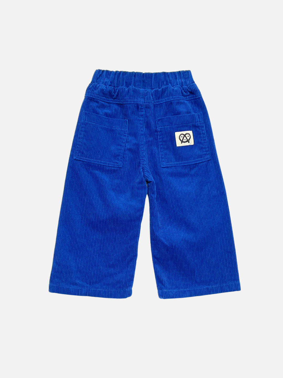 Blue | A pair of bright blue corduroy pants for toddlers, shown from the back. The pants feature an elastic waistband, two back pockets, and a small white square patch with a black logo on the upper right pocket.
