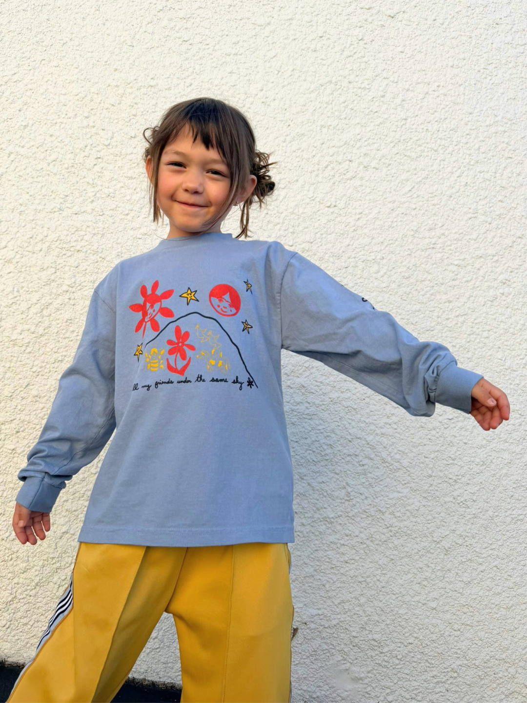 Blue | Child wearing a blue sweater with colorful designs against a white wall