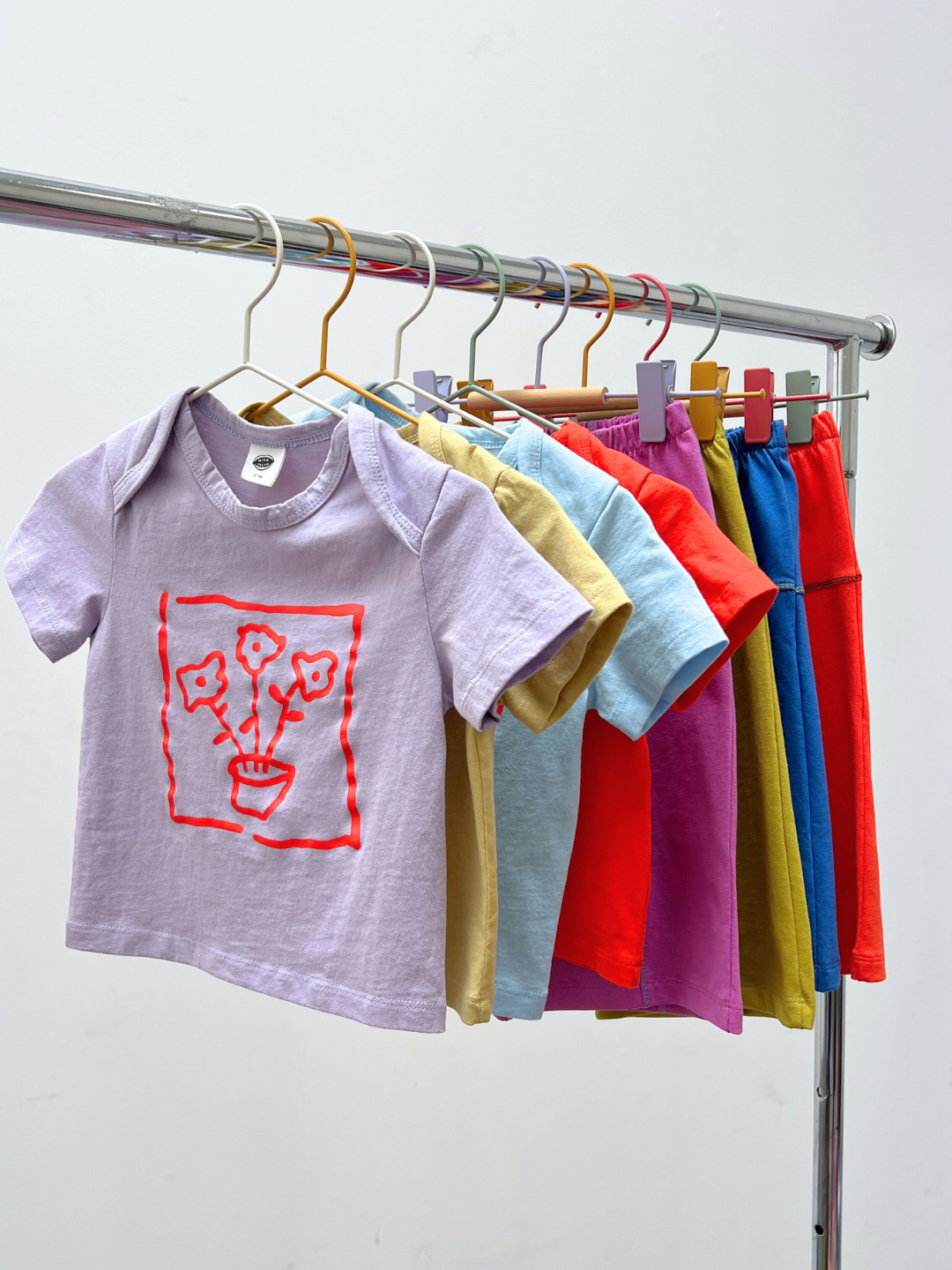 Lavender | Children's t-shirts in various colors hanging on a rack against a white background