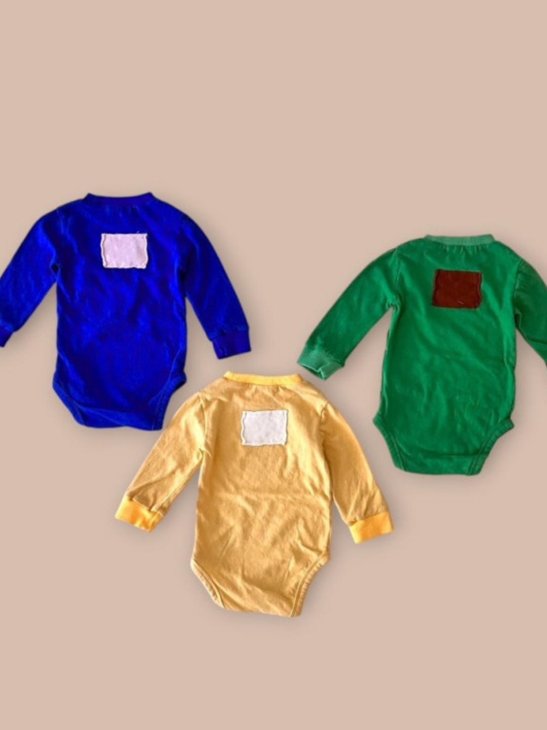 Onesies in blue, green and yellow laid flat 