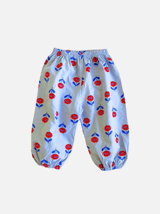 Image of Front view of Baby Blossom Pant. Light blue pant with red flower with dark blue stem print all over. 