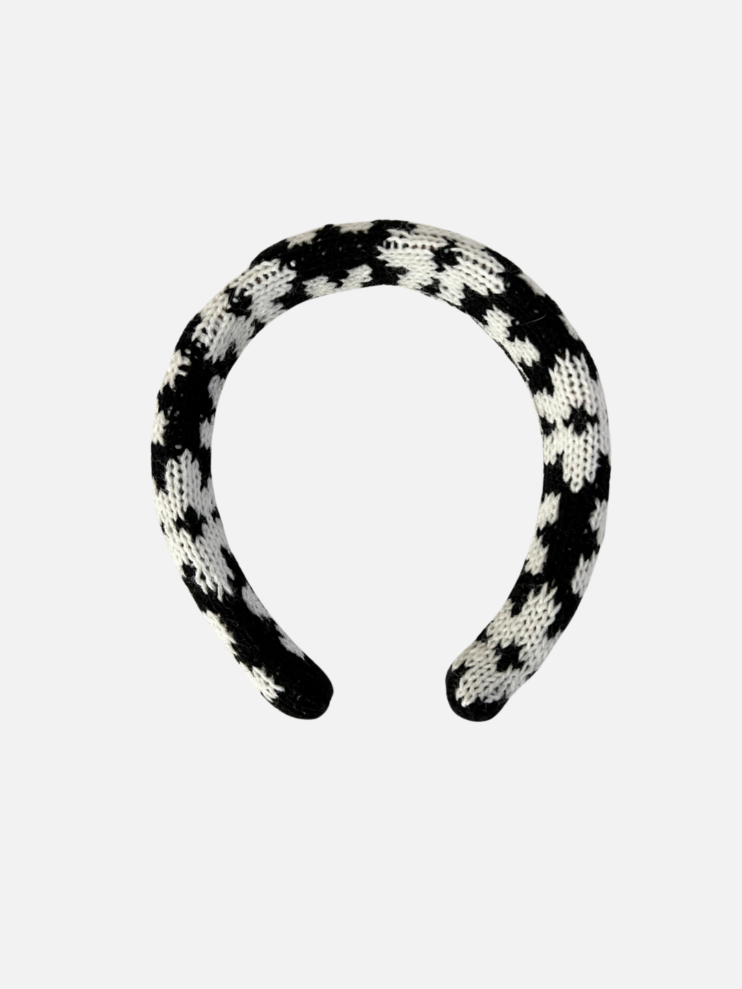 A kids' knitted headband in a pattern of white flowers on a black background