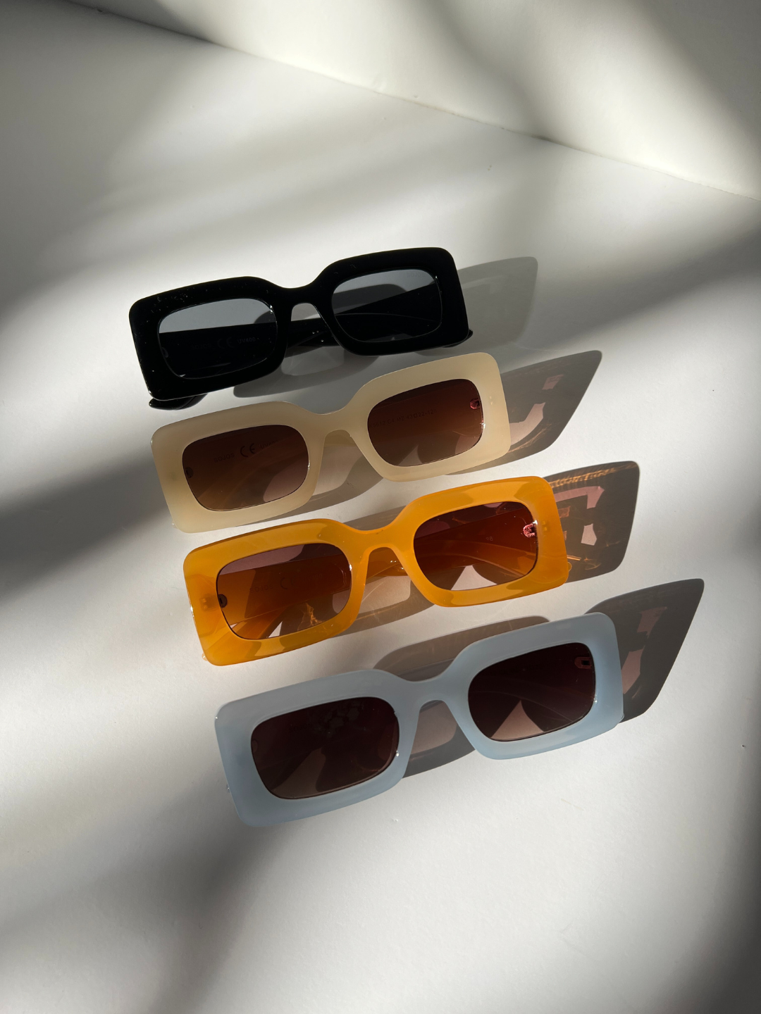 Blue | Group of kids rectangle sunglasses in black, blue, orange and cream, lined up diagonally on a white background.
