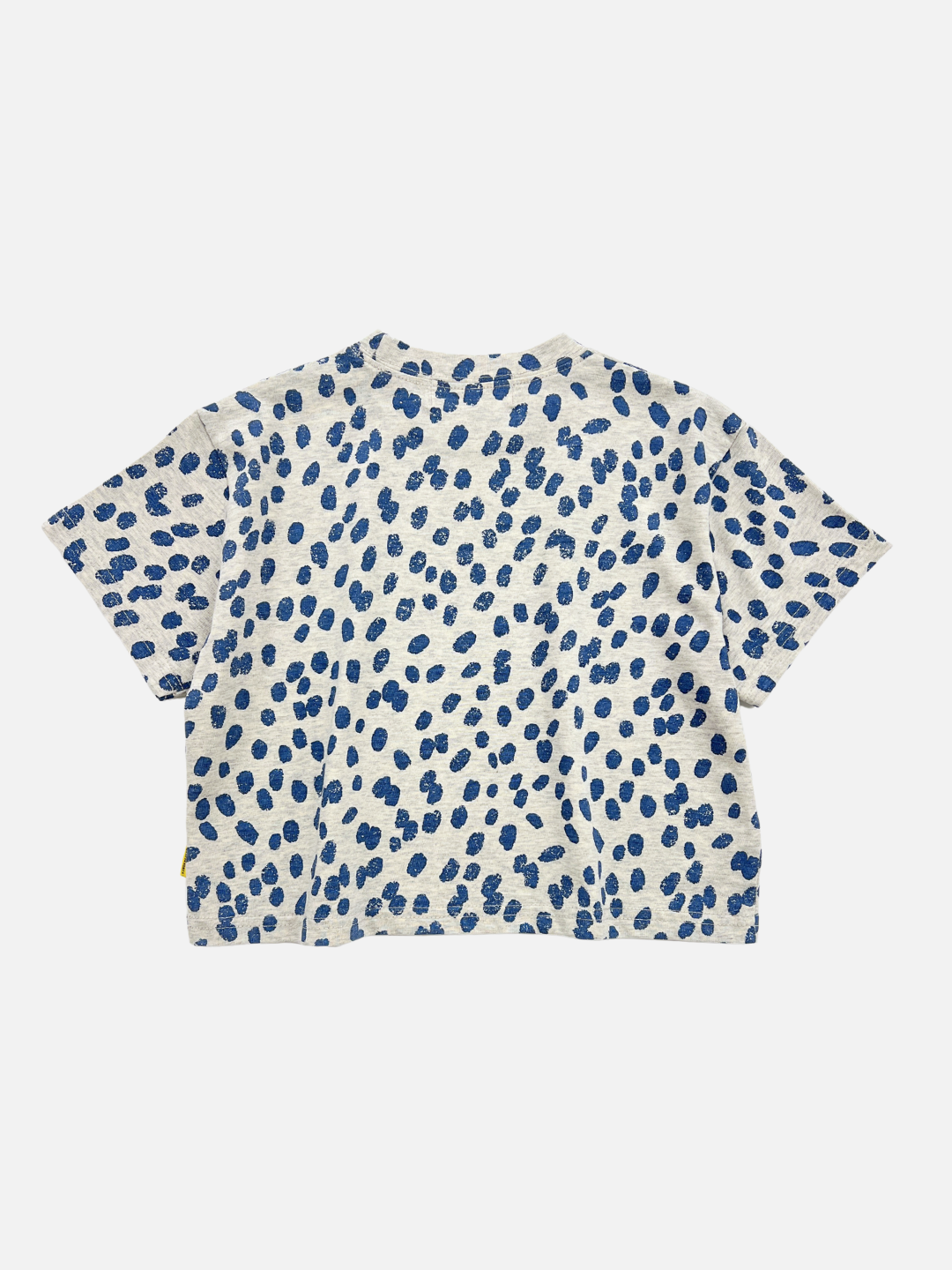 Back view of the kids' Spotted Tee. Warm pale gray background with navy blue spots all over.