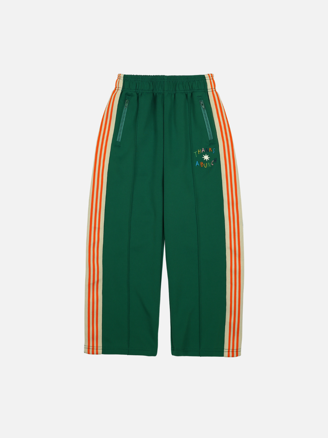 Green | The THANKS TRACK PANTS in green feature orange and white side stripes, an elastic waistband, and zippered pockets. Embroidered text and design on the left thigh add a stylish touch, making them ideal for both merchandising and casual wear.