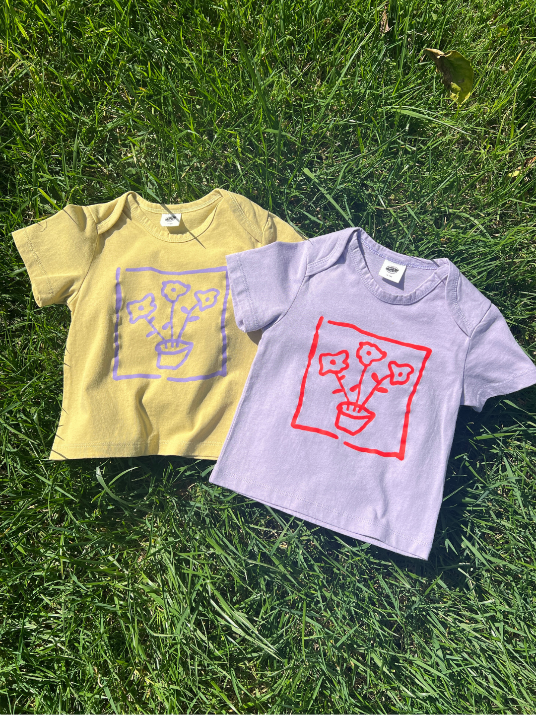 Yellow and lavender t-shirts with graphic designs on grass