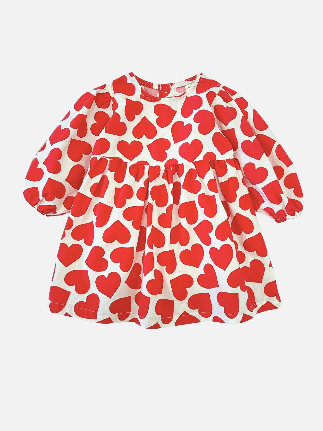 Kids dress in white with red hearts printed closely all over, with a round neck, high waist, long puffed sleeves and a loose, voluminous shape.