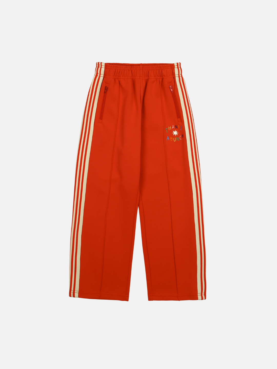 Red | THANKS TRACK PANTS in red, featuring white side stripes and an elastic waistband with a small graphic on the left thigh. Perfect for merchandising, these pants seamlessly blend style and comfort.