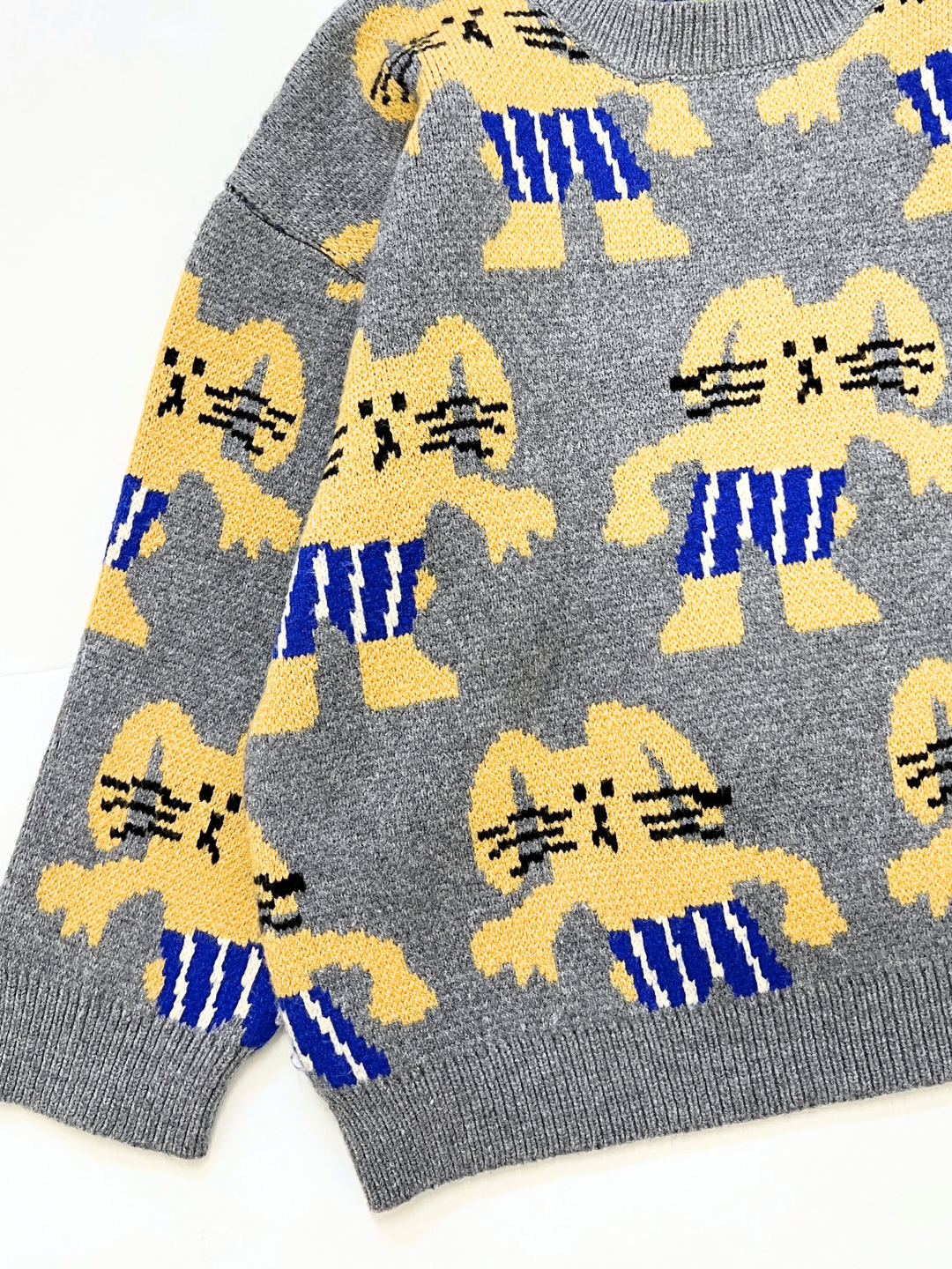 The MAX SWEATER is gray and features a repeating pattern of yellow cartoon bunnies in blue and white striped pants.
