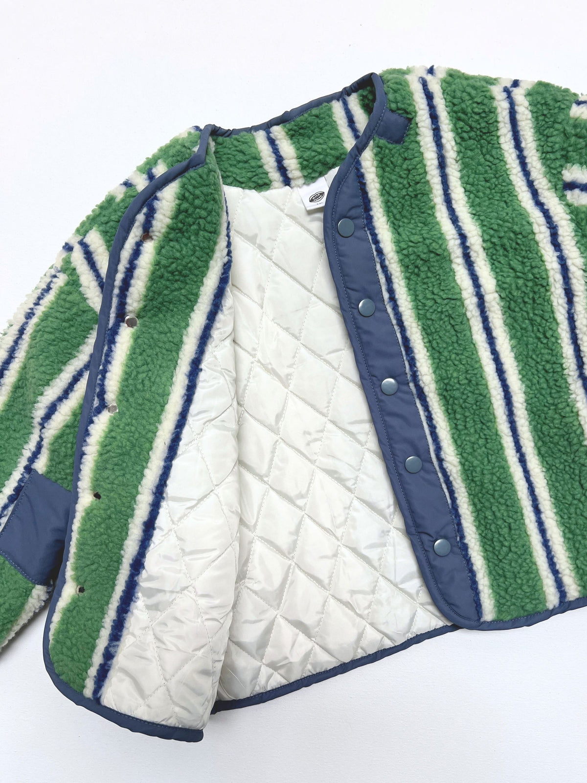 Open sherpa jacket showing the cream quilted lining and blue snap placket.