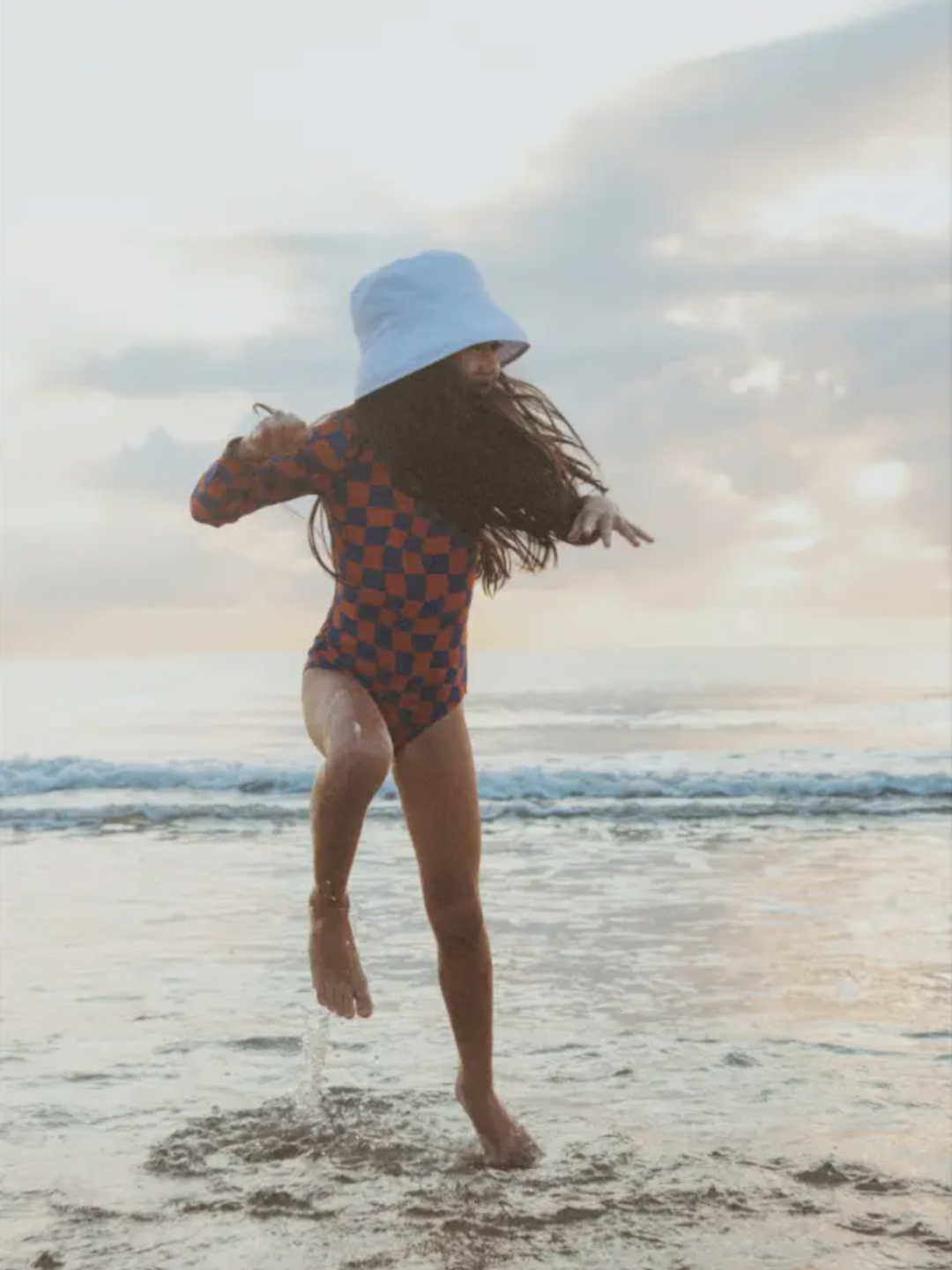 A child is wearing Wavy Checks One-Piece Swimsuit, playing in the water