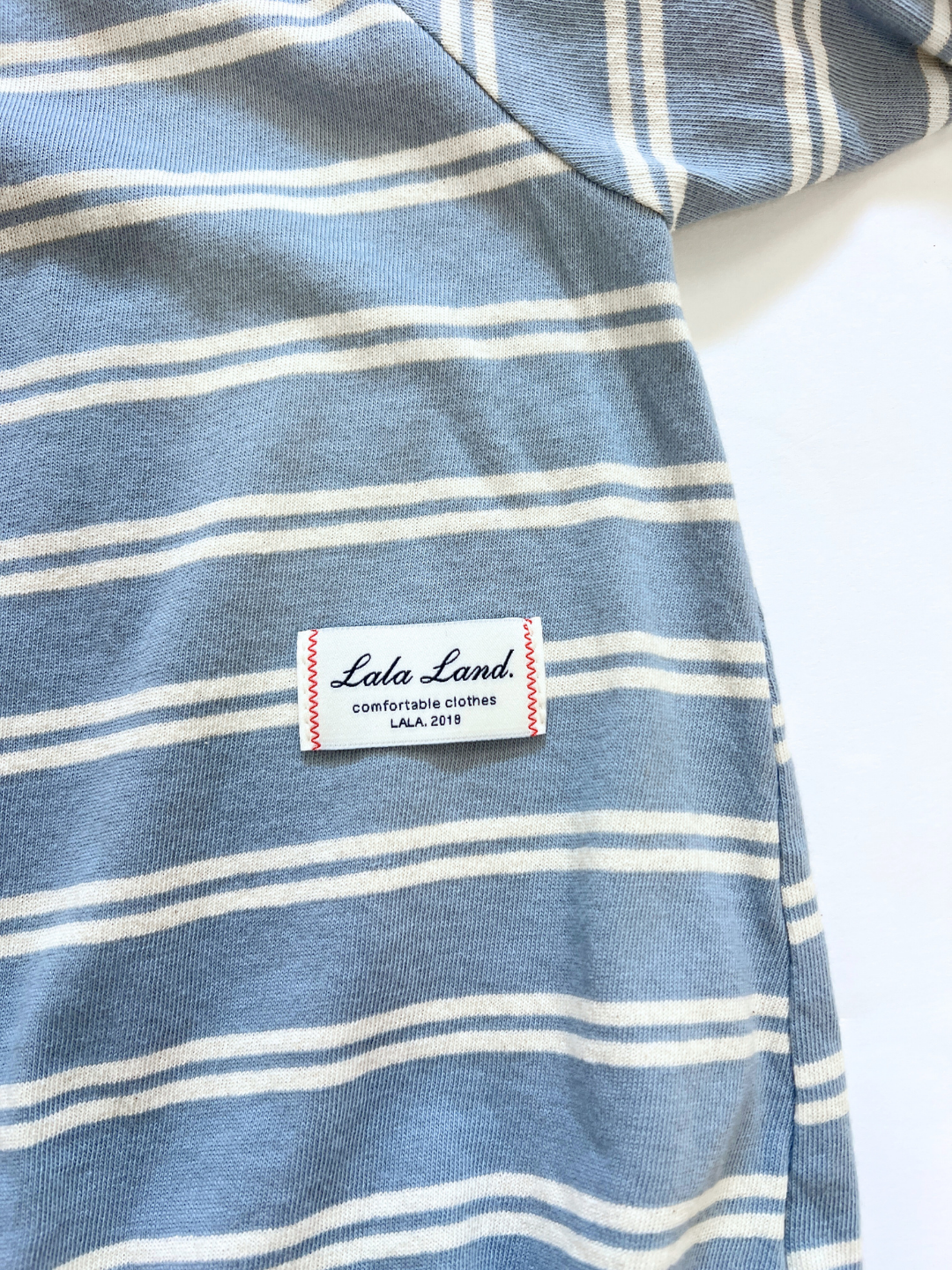The SLOUCHY STRIPE ROMPER is a blue and white striped cotton jersey shortie from a popular Korean baby brand, featuring a sewn label with "Lala Land comfortable clothes LALA 2018.