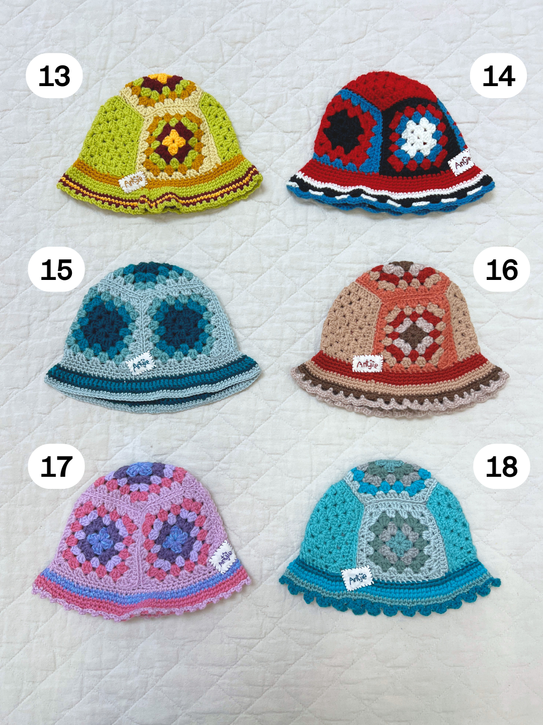 A hand-made CROCHETED BUCKET HAT 1-3Y in color #13, inspired by South African artisan style, features a vibrant geometric pattern and is displayed on a quilted surface.
