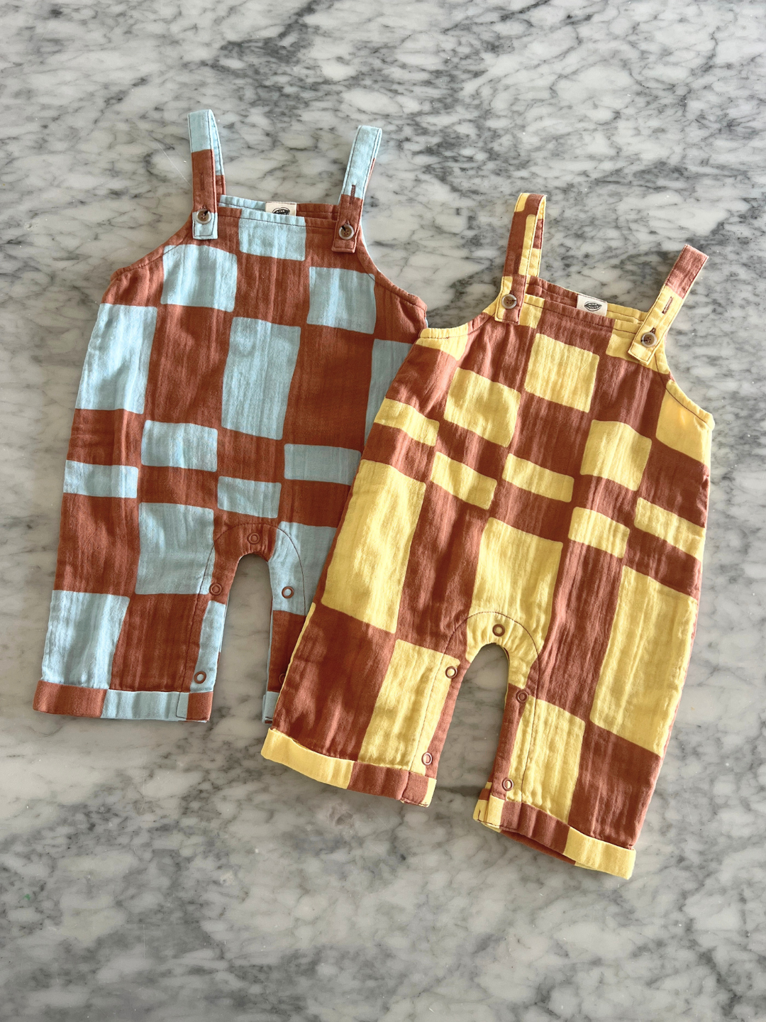 Yellow Checkers | Two pairs of checkered overalls on a marble table background
