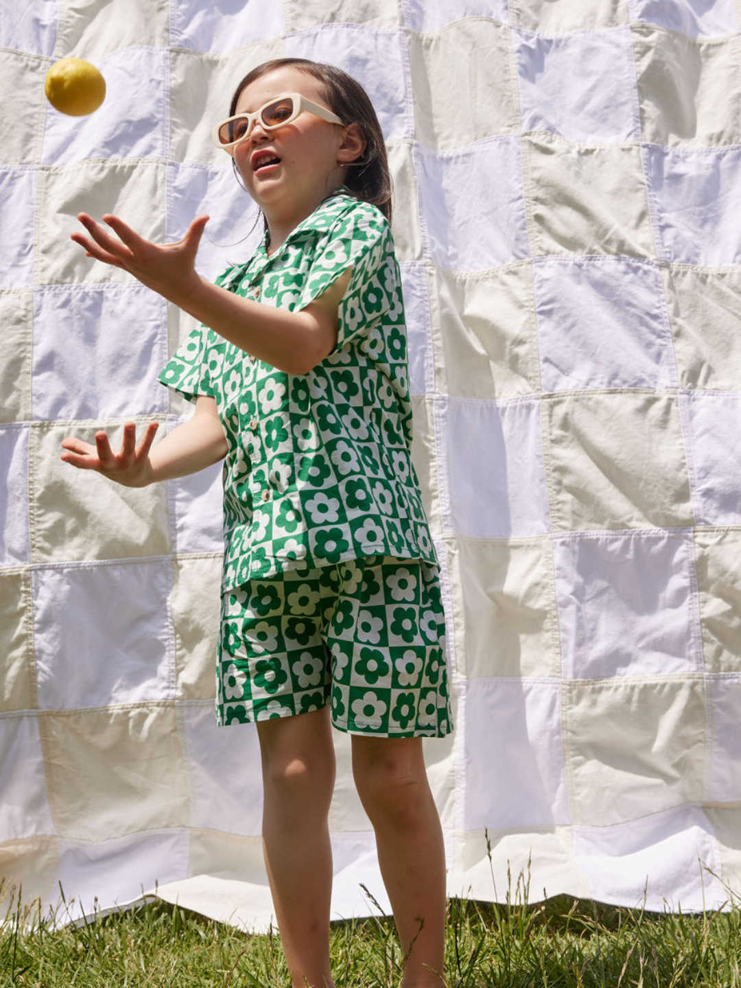 Child wearing a kids' short set in a checkerboard pattern of green and white flowers