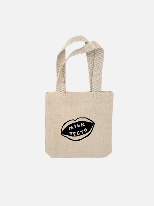 Image of  Milk Teeth mini tote front view. Cotton tote with Milk Teeth mouth logo in the center.