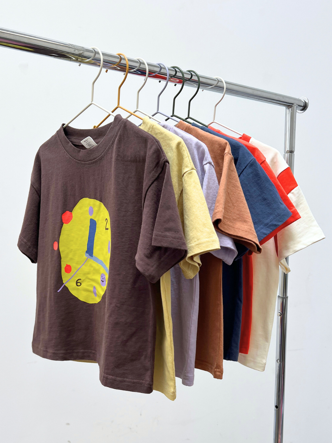 Colorful t-shirts hanging on a rack against a white background