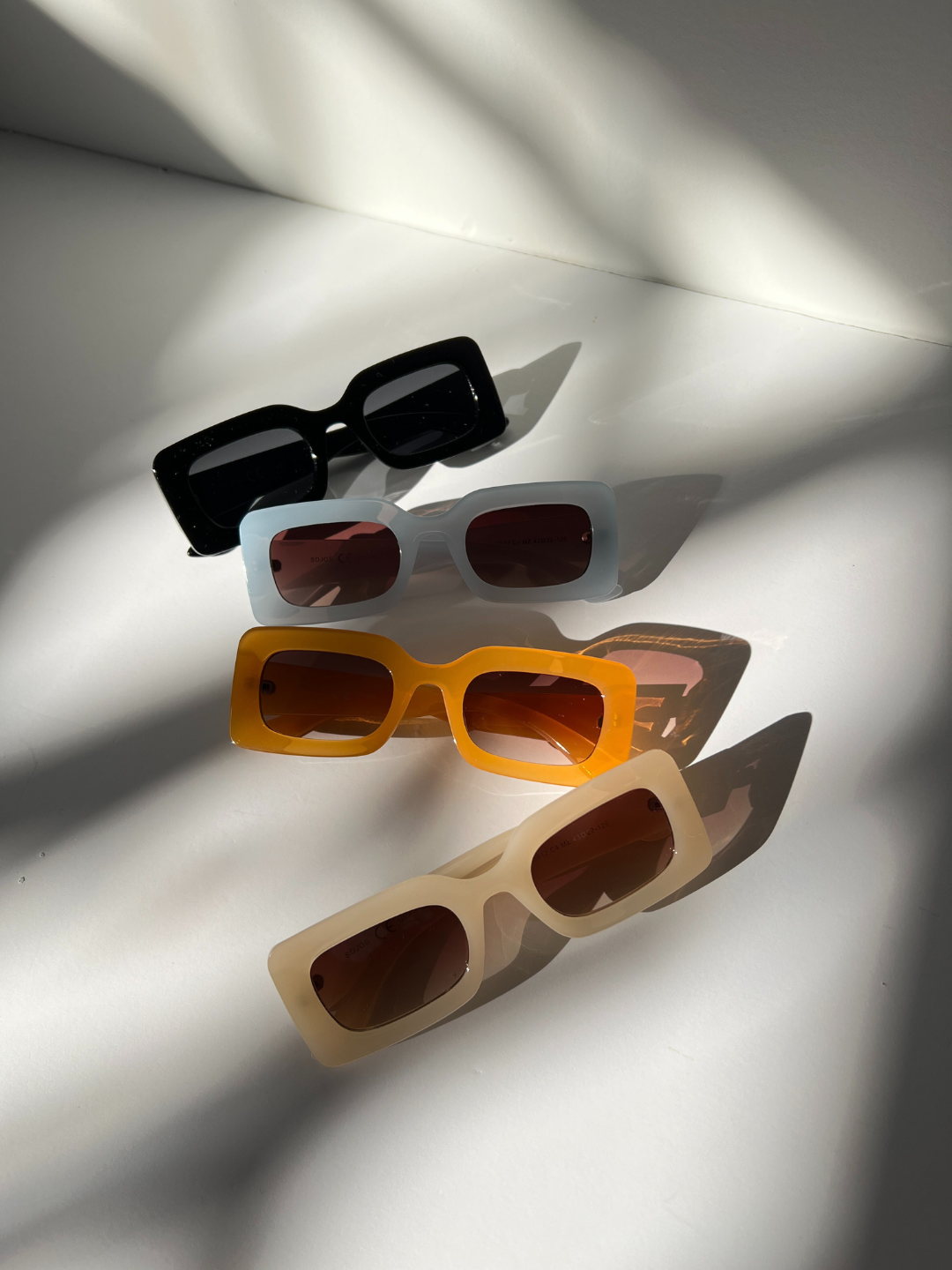 Cream | Group of kids rectangle sunglasses in black, blue, orange and cream, arranged on a white background.