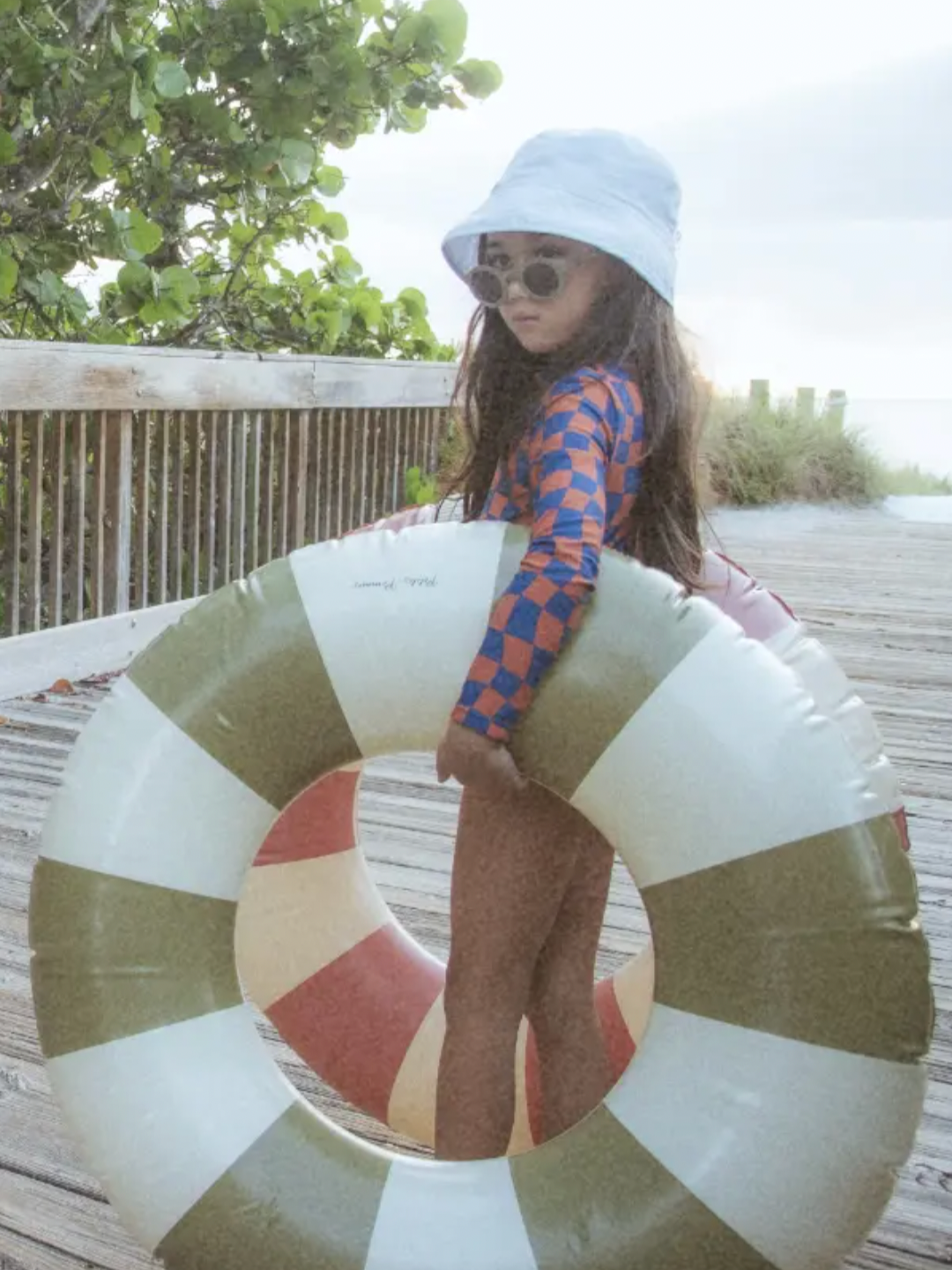 A child is wearing Wavy Checks One-Piece Swimsuit,  getting ready to go to the beach. 